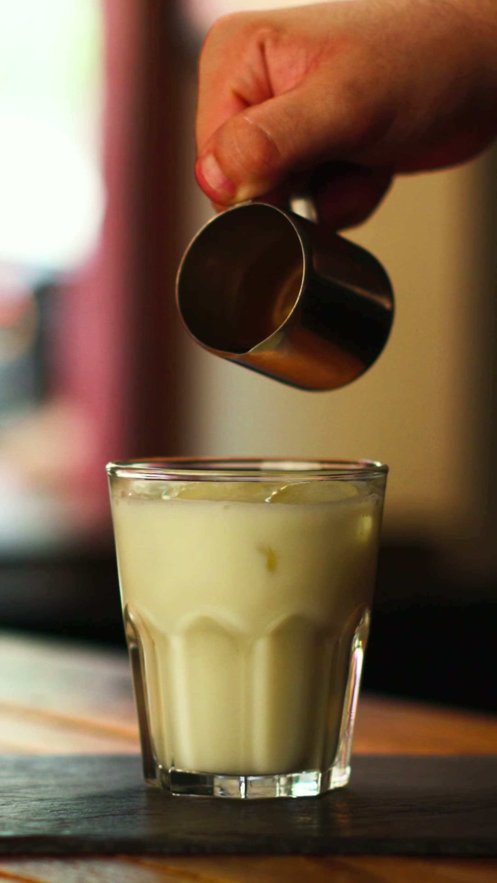 Milch wird in ein Glas mit dem Signature-Drink Antonietta gegossen, Standbild aus einem Reel für Café Jlöcklich